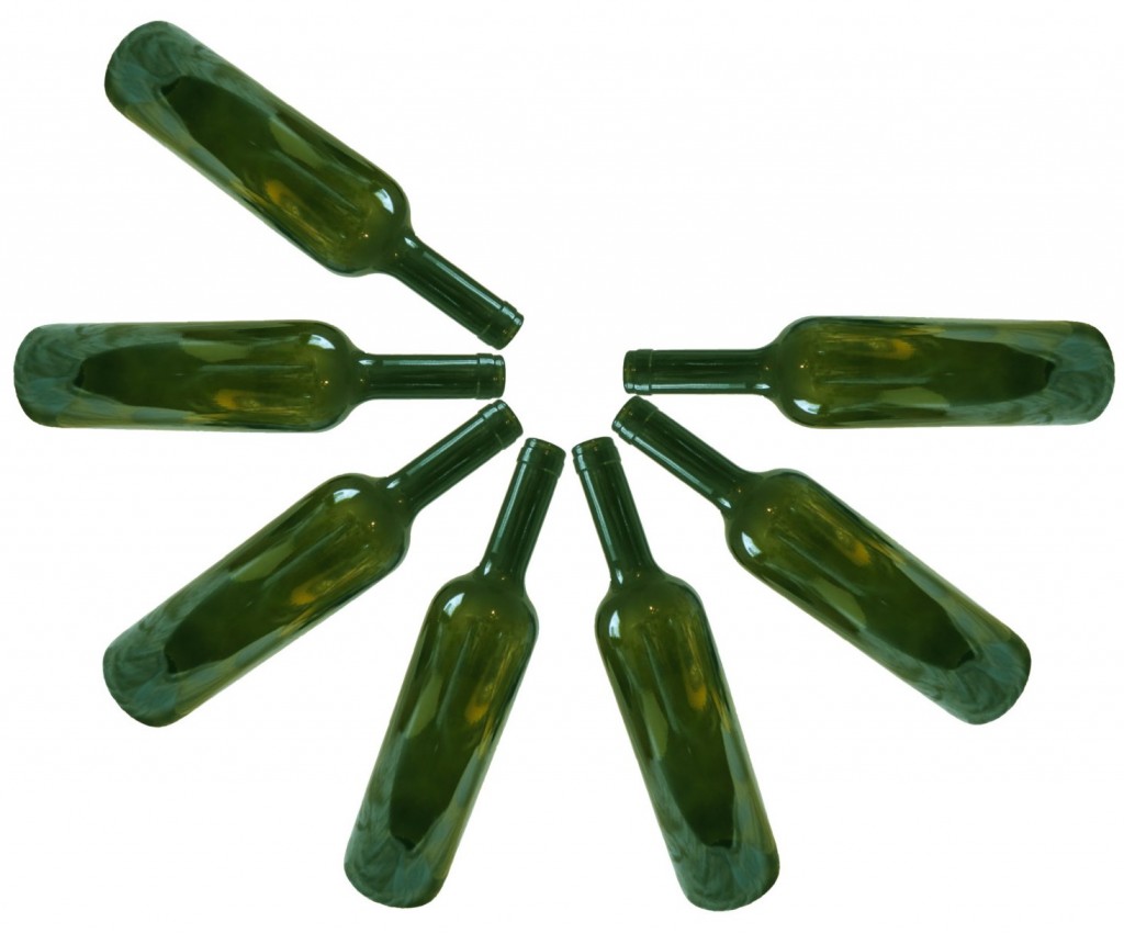 Seven empty green wine bottles