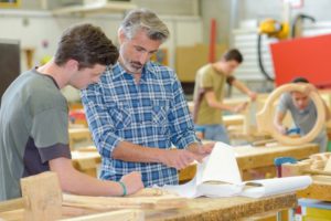 Teacher helping student in woodwork class